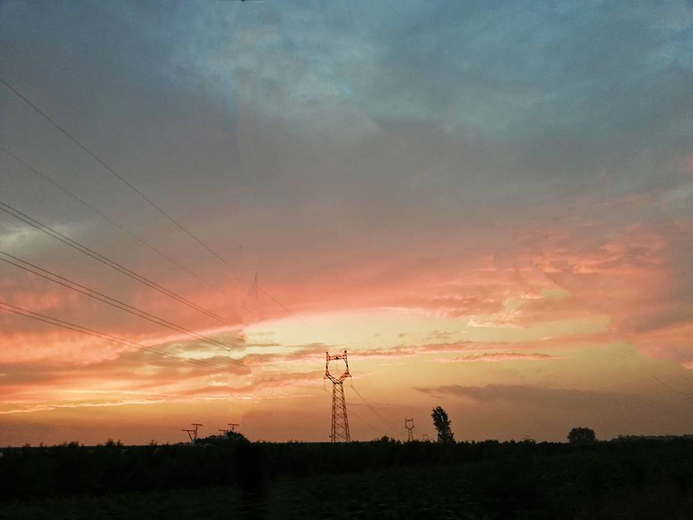 夕阳似乎在金红色的彩霞中滚动，然后沉人阴暗的地平线后面。通红的火球金边闪闪，迸出两三点炽热的火星，于是远处树林暗淡的轮廓便突然浮现出连绵不断的浅蓝色线条。