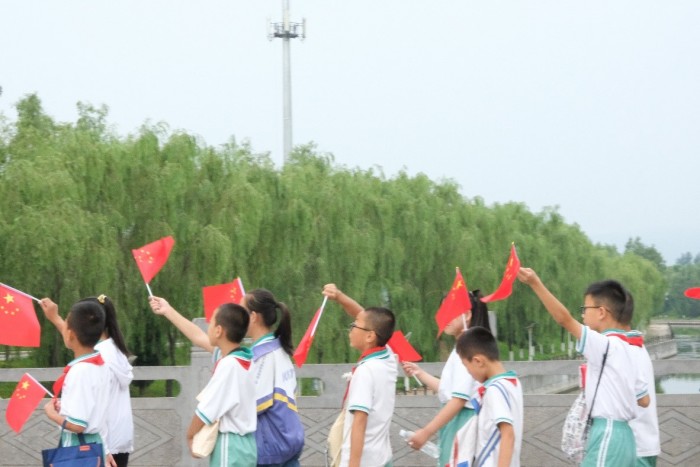 行进途中孩子们手舞国旗.jpg 行进途中孩子们手舞国旗.jpg