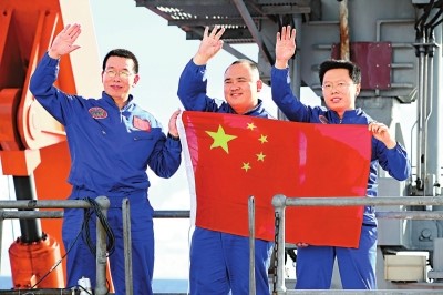 △2012年6月24日，“蛟龙”号三位试航员崔维成、叶聪、杨波（左至右）手举国旗向众人致意。