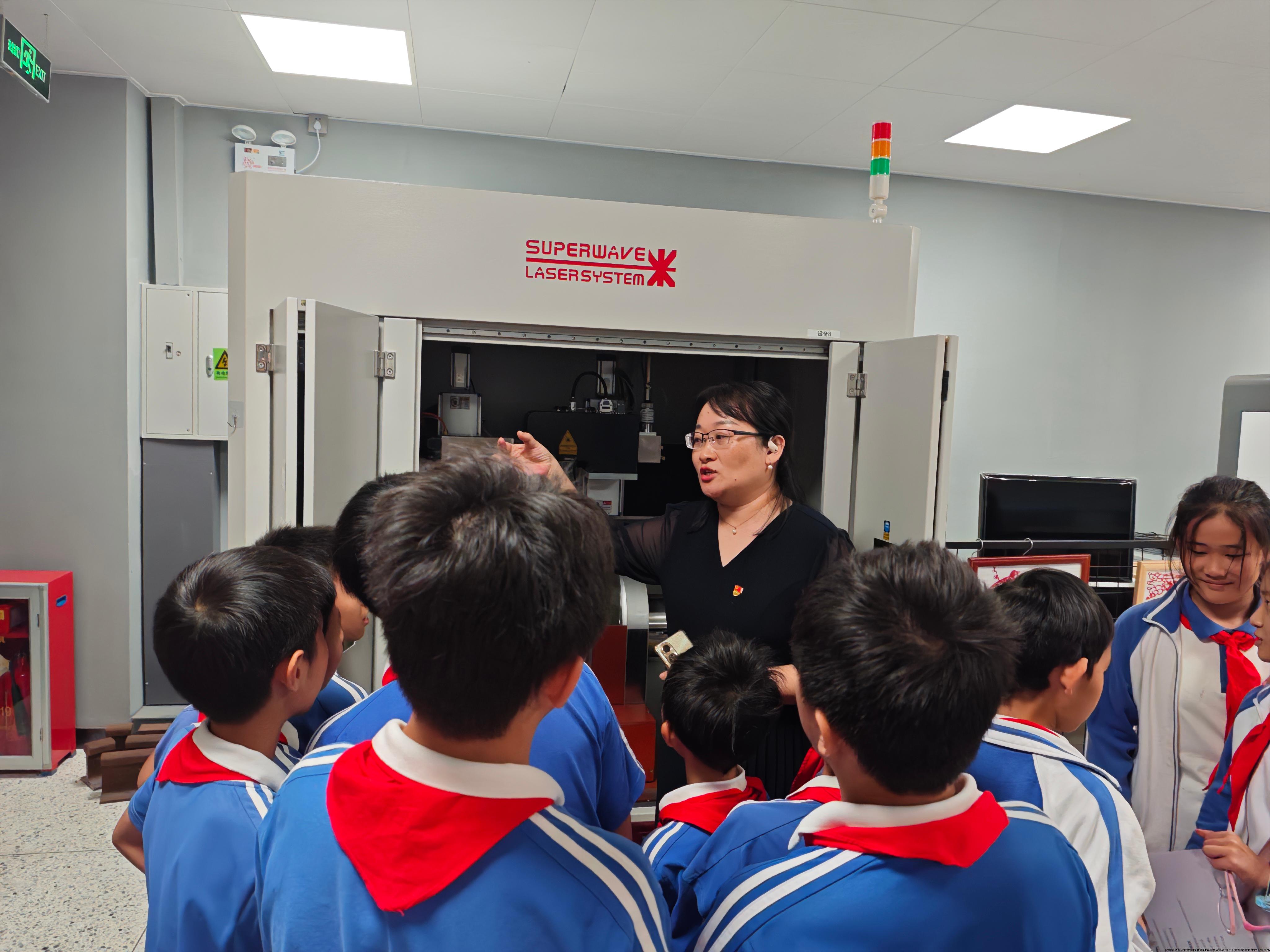 小同学们热切地围绕在老师和大哥哥大姐姐们身边了解“大机器”——激光加工设备的功能和技术特点